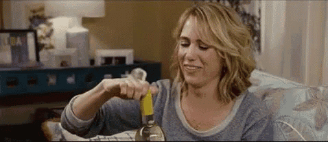 a woman is opening a bottle of wine while sitting on a couch .