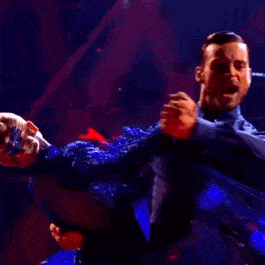 a man and woman are dancing on a stage with red lights behind them