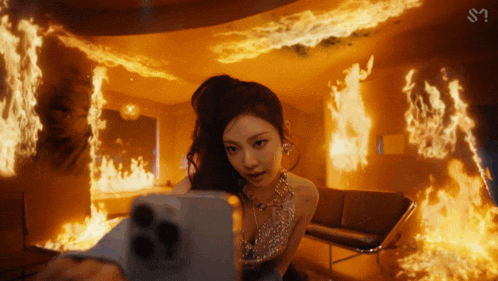 a woman is taking a picture of herself in front of a burning room