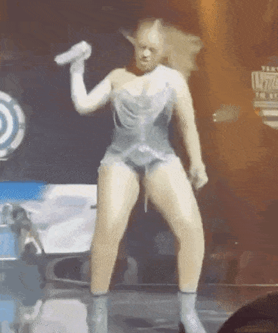 a woman is dancing on a stage while holding a microphone in her hand .
