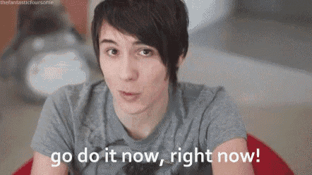 a young man in a grey shirt is sitting on a red bean bag chair and says go do it now , right now .