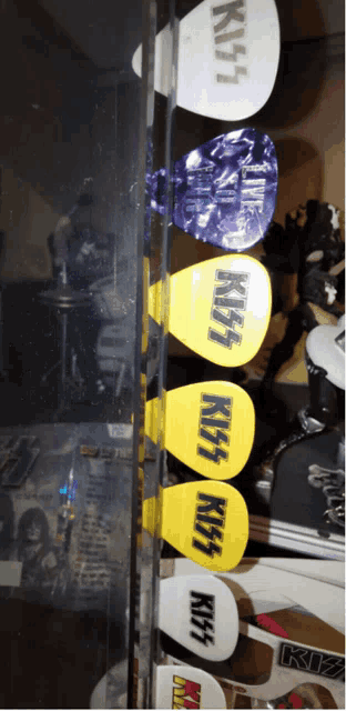 a row of kiss guitar picks are lined up in a display case