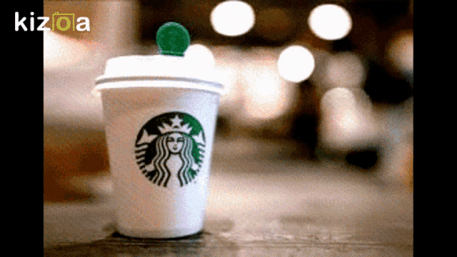 a starbucks cup sits on a table in front of a kizboa logo