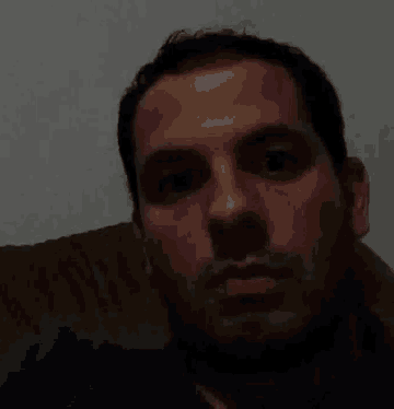 a man is sitting on a couch looking at the camera with a serious look on his face .