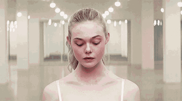 a woman with blonde hair and blue eyes is standing in a hallway looking at the camera