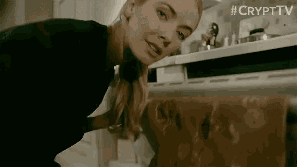 a woman is looking into a refrigerator with a ghost in it .