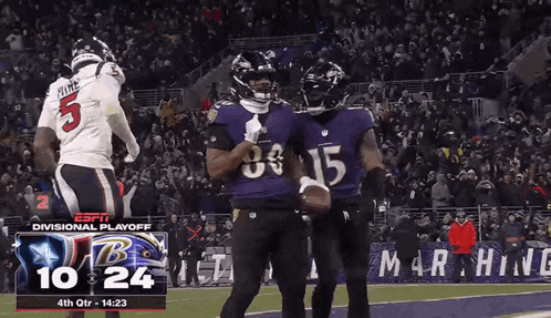 two ravens players are celebrating a touchdown in front of a large crowd