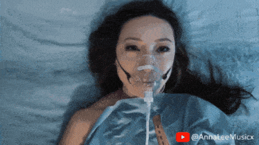 a woman laying in a hospital bed with an oxygen mask on