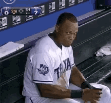a baseball player is sitting on a bench in the dugout