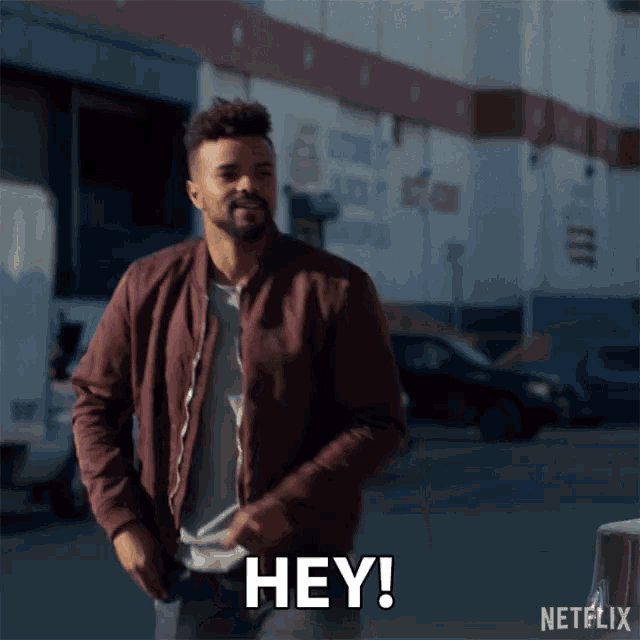 a man in a maroon jacket says " hey " in front of a building