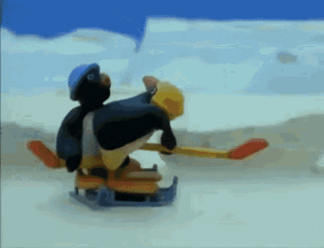 two penguins are sledding down a snowy hill .