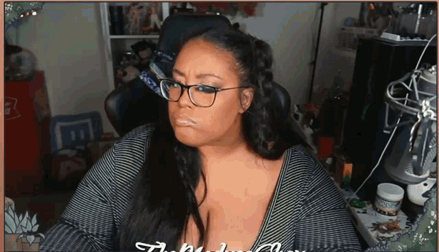 a woman wearing glasses and a striped shirt is sitting in front of a coca cola cooler