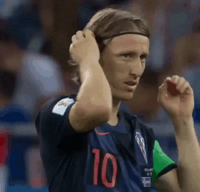 a soccer player wearing a headband is adjusting his hair while standing on the field .