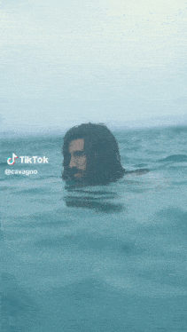 a man with long hair and a beard is swimming in the ocean .