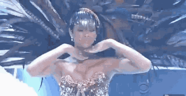 a woman is making a heart shape with her hands on her chest .