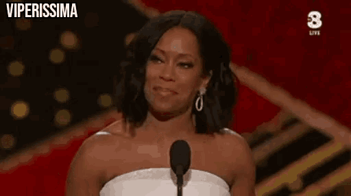 a woman in a white dress stands in front of a microphone with the words viperissima written on the bottom