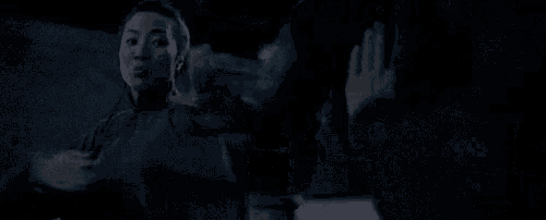 a woman is holding a child 's hand in a dark room .