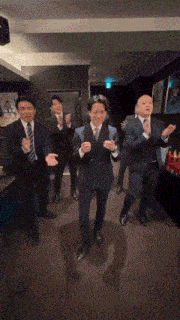 a group of men in suits are dancing in a room