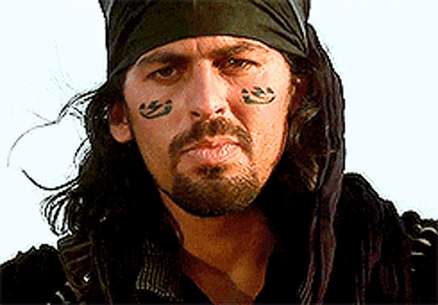 a man with a beard and a bandana on his head has a smiley face painted on his face ..
