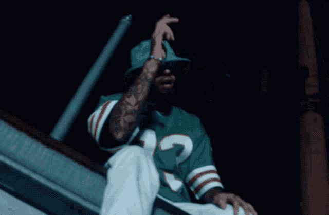 a man wearing a green hat and a jersey that says miami on it