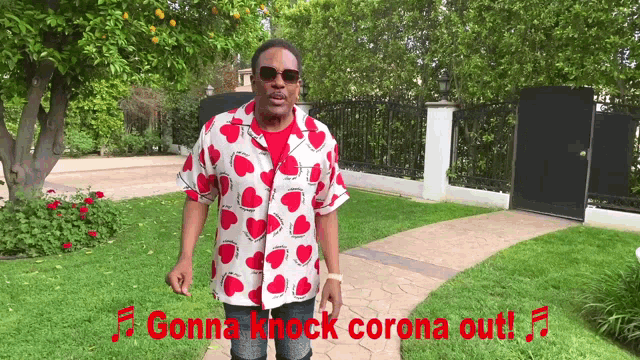 a man wearing a red and white shirt with hearts on it says gonna knock corona out in red