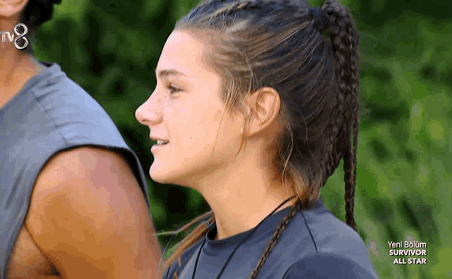 a woman with a braided ponytail stands next to a man with a tv8 logo on his neck