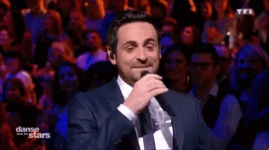 a man in a suit singing into a microphone with danse des stars written on the bottom