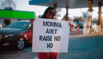 a woman holds a sign that says momma ain t raise no ho
