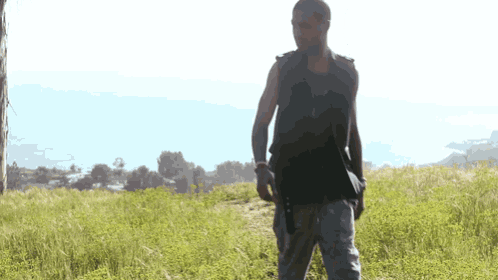 a man in a black vest is walking through a field