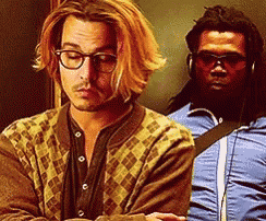 a man with long hair and glasses is standing next to another man