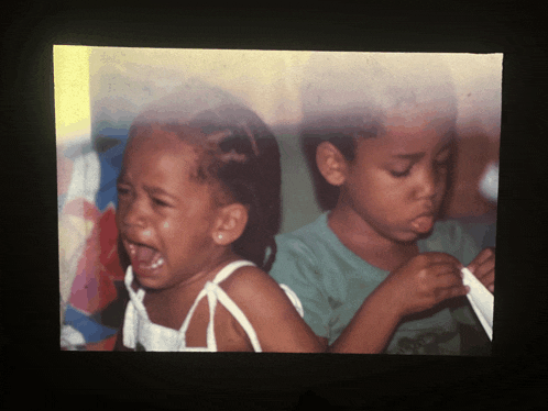 a boy and a girl are sitting next to each other and one of the girls is crying