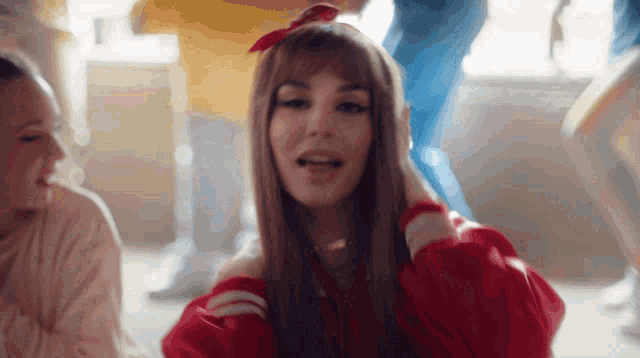 a woman in a red sweater is sitting on the floor with her mouth open
