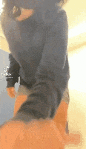 a person wearing a blue sweater and shorts is standing in a room with their legs crossed .