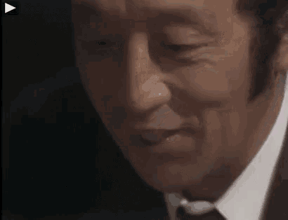 a close up of a man 's face in a suit and tie with his eyes closed .
