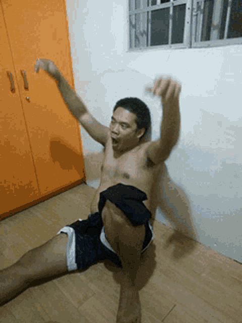 a shirtless man in shorts is laying on the floor with his arms outstretched