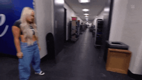 a woman is standing in a hallway with a trash can and a trash can .