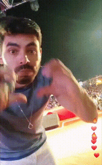 a man with a beard and mustache is making a heart shape with his hands
