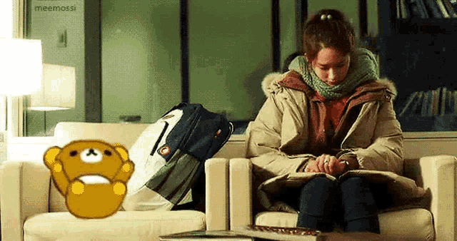 a woman is sitting on a couch reading a book with a teddy bear behind her ..