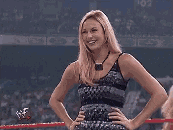 a woman in a sequined dress is standing in a wrestling ring .