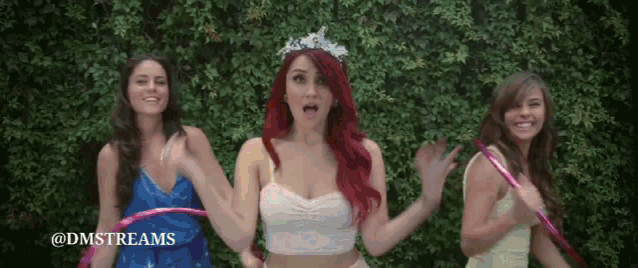three women are holding hula hoops in front of a green hedge and the hashtag @dmstreams