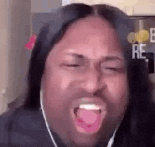 a man with long hair is making a funny face with his tongue out .
