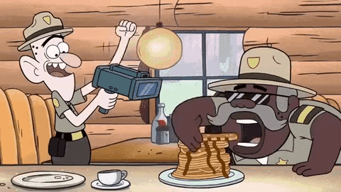 two cartoon characters are sitting at a table with pancakes and a camera