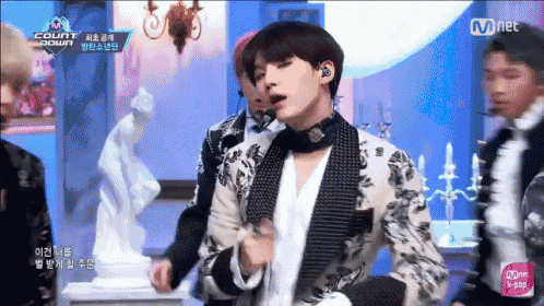 a group of young men are performing on a stage with a mnet advertisement in the corner