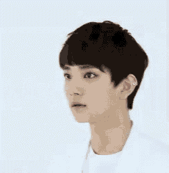 a young man with short hair is wearing a white shirt
