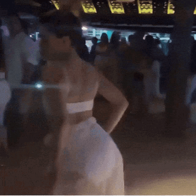 a woman in a white dress is dancing in front of a crowd