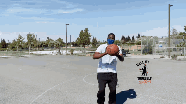 a man wearing a mask is throwing a basketball in the air with the words ball by yourself behind him