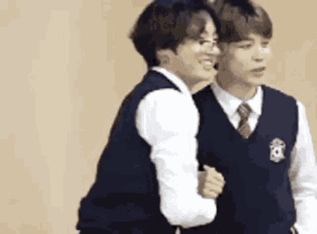 two young men in school uniforms are hugging each other while standing next to each other .