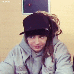 a person with dreadlocks wearing a hat and a hoodie that says kaulititz