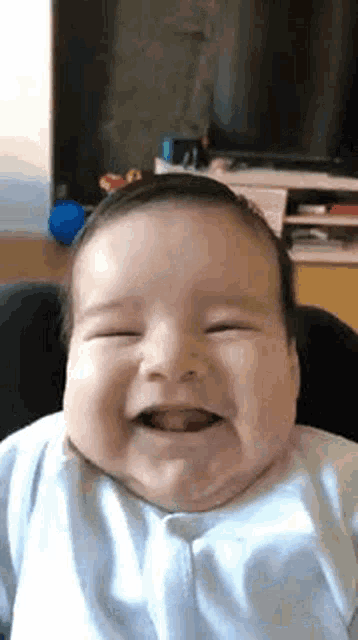a baby is smiling while sitting in a high chair in a living room .