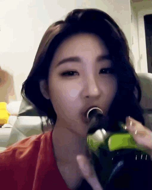 a woman is drinking from a green bottle with a green label